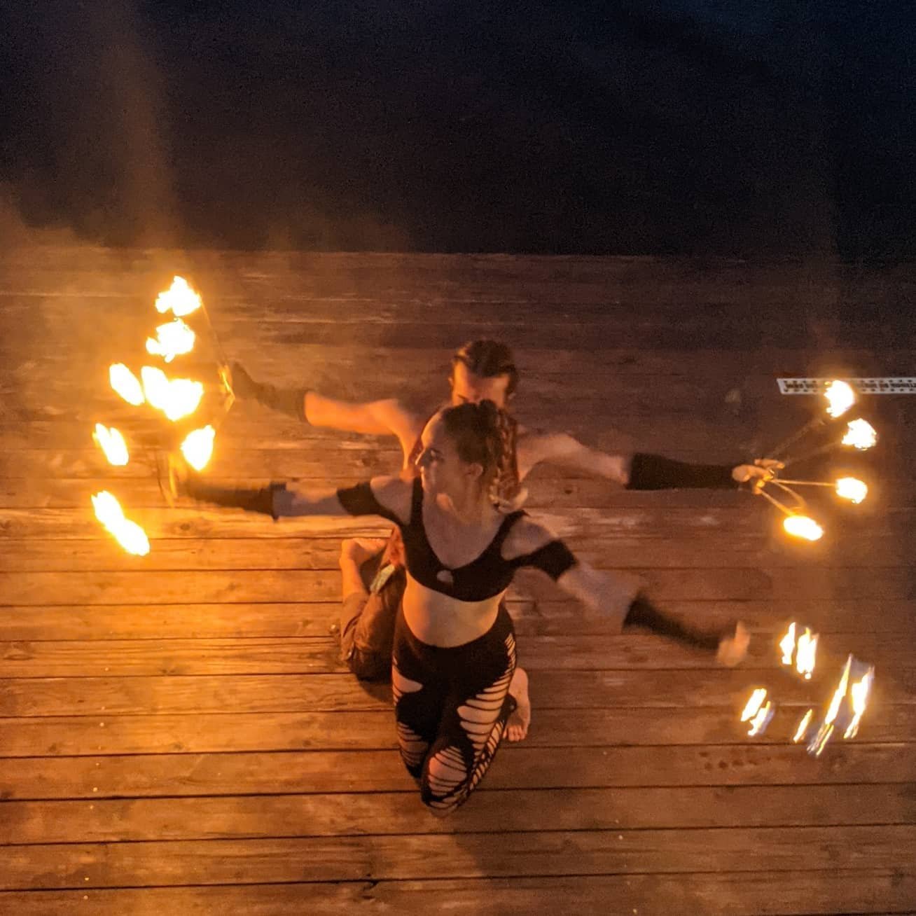 Fire performers spinning flames on the deck at night during Glow Worm Night