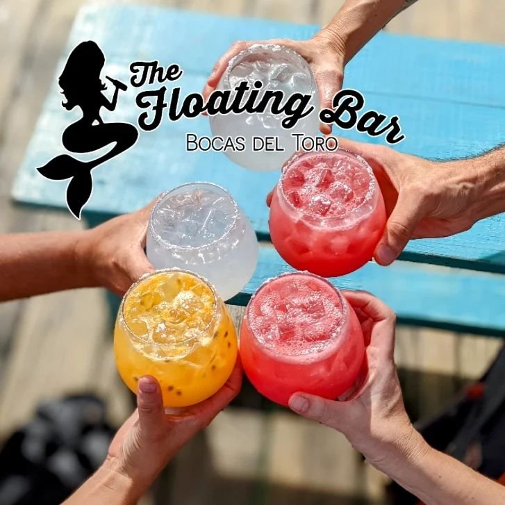 Four hands raising colourful cocktails in a toast on deck