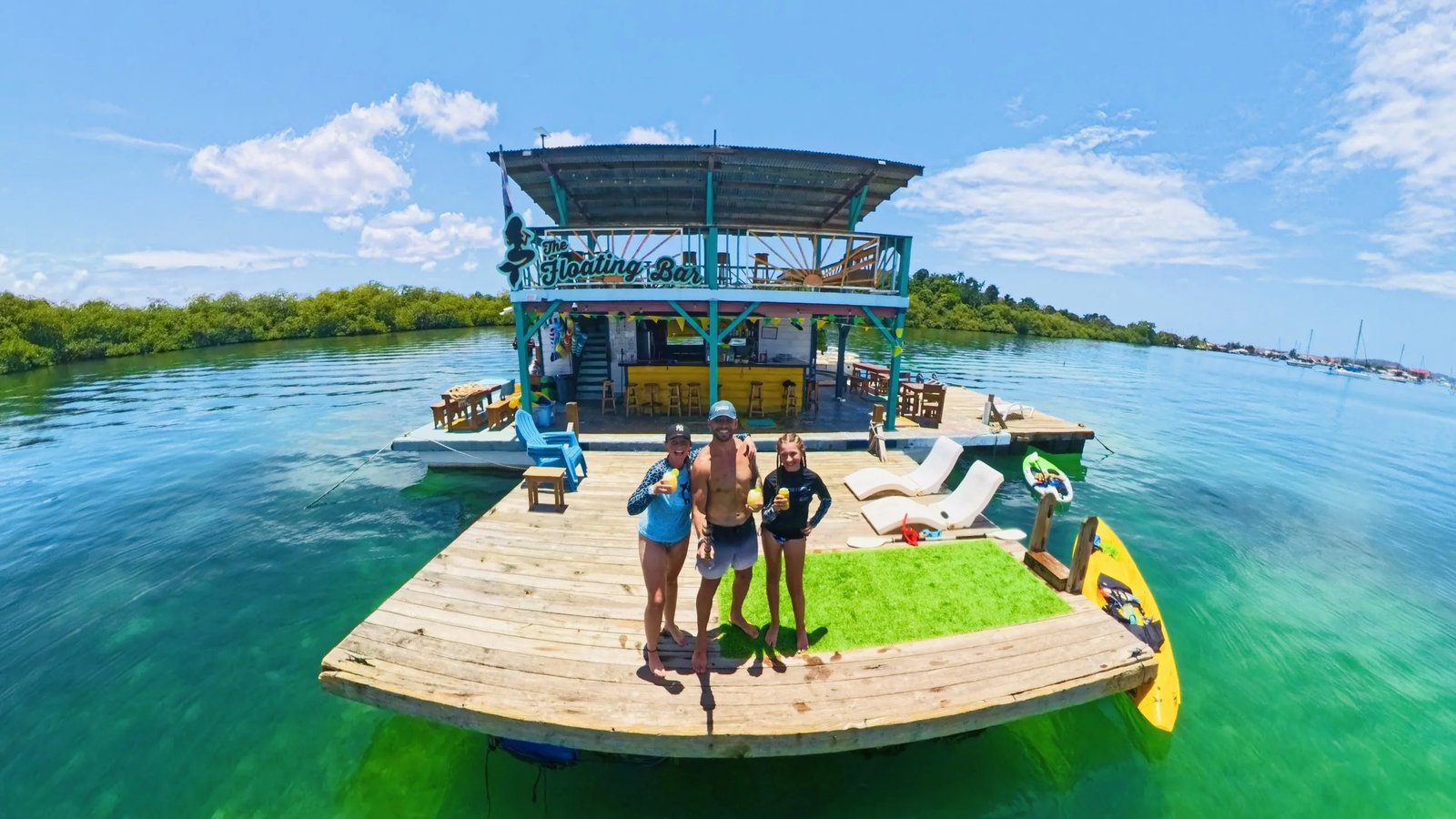 Guests with drinks standing on the swim deck in front of the bar